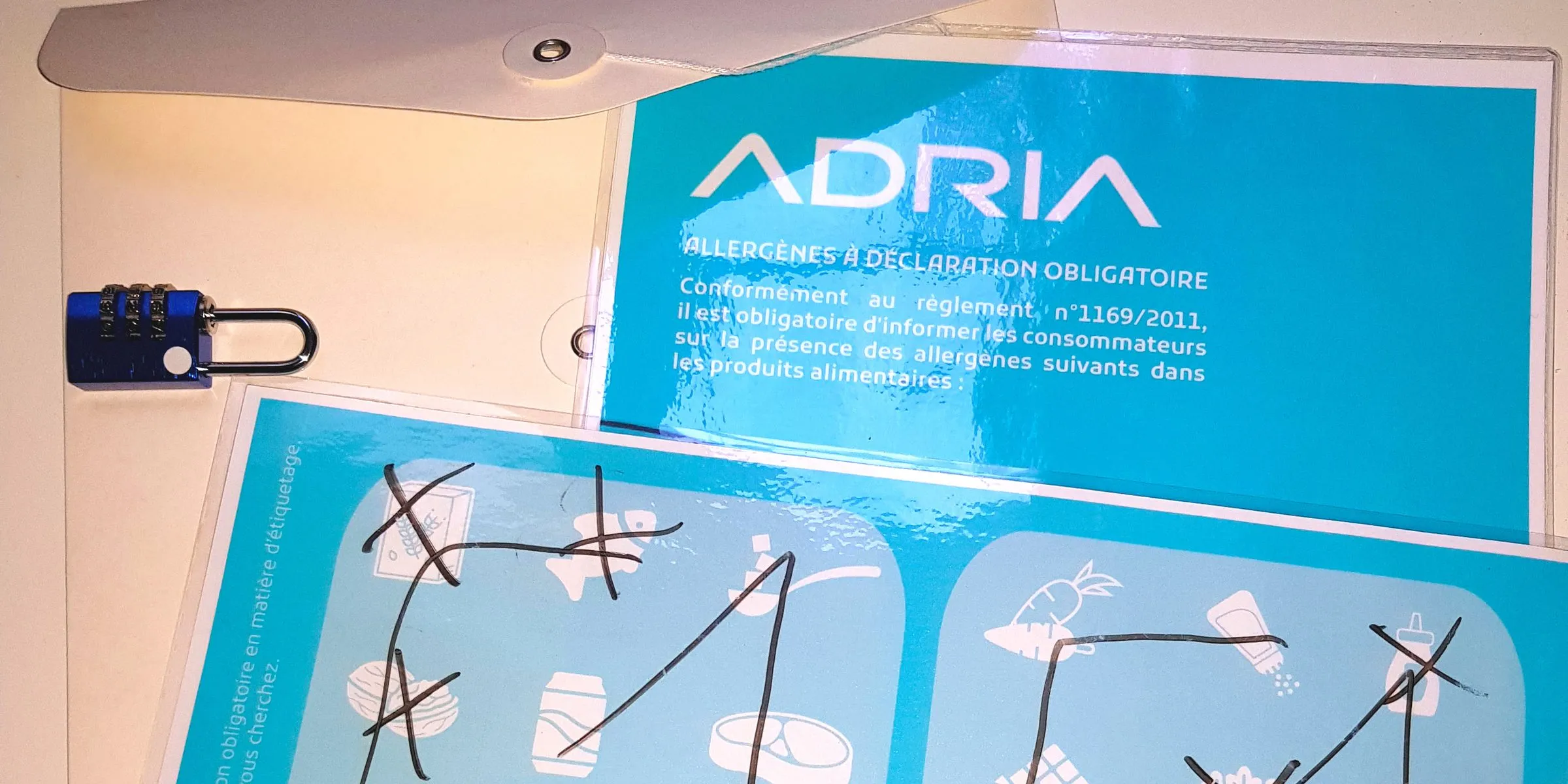 Escape game conçu pour l'ADRIA : fiche « Allergènes à déclaration obligatoire » et grille de pictogrammes barrés au feutre, à côté d'un cadenas à code