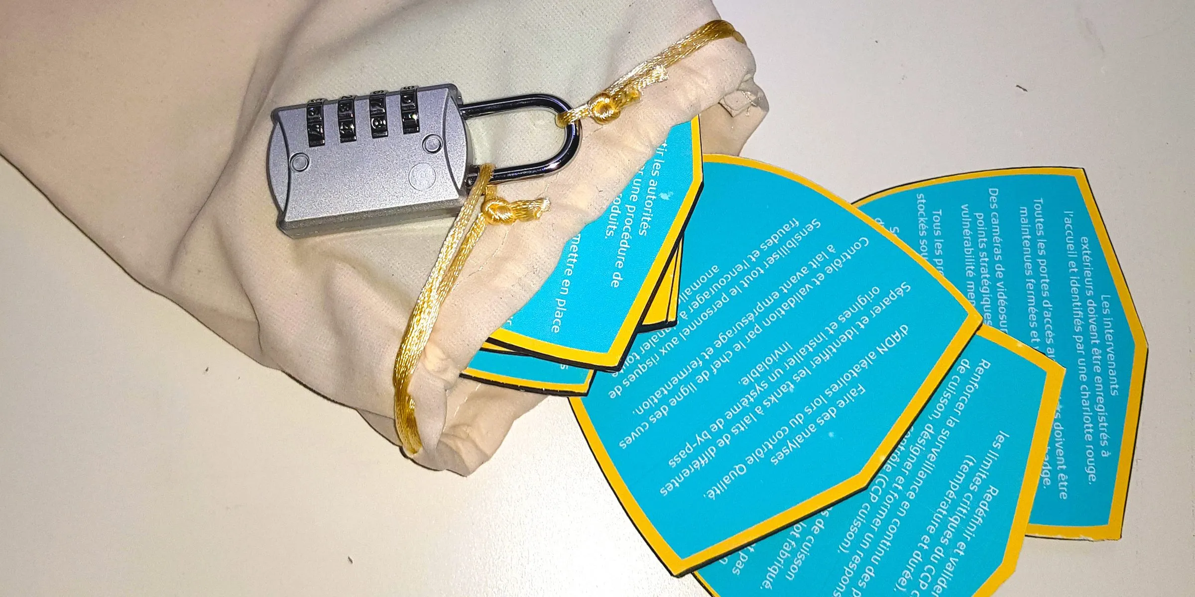 Escape game conçu pour l'ADRIA : pochon fermé par un cadenas à code et cartes de mesures de sécurité des aliments (contrôle qualité, limites critiques du CCP cuisson, accueil des intervenants extérieurs)