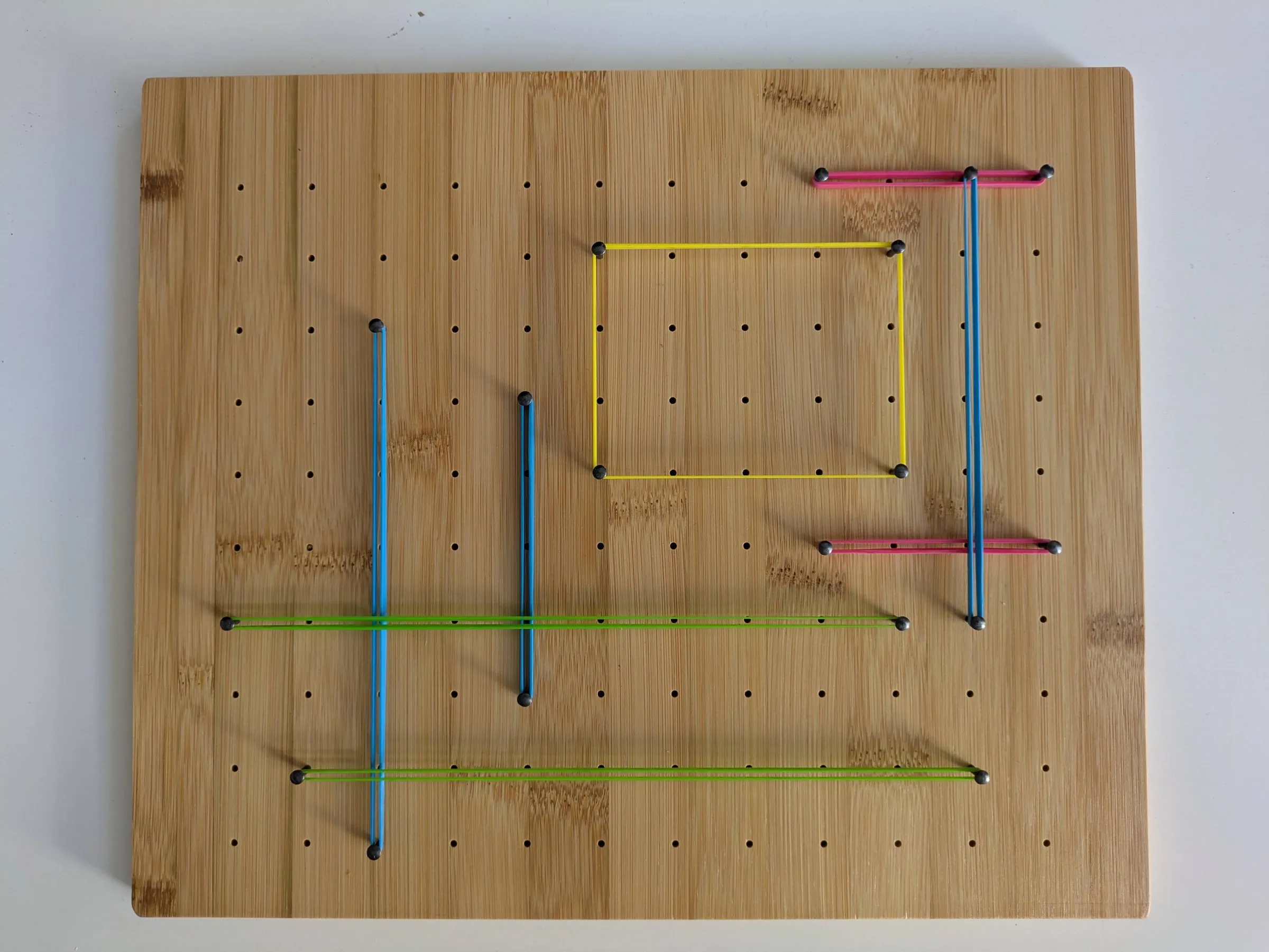 Finovox : œuvre en élastiques de couleur tendus sur une planche de bambou à chevilles, accessoire fabriqué pour l’une des énigmes