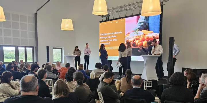 Le Grand Replay conçu pour Novonesis : en plénière, l'écran de scène affiche la question « Combien de recettes de fromage type Feta réalisons-nous chez Novonesis ? » devant les équipes