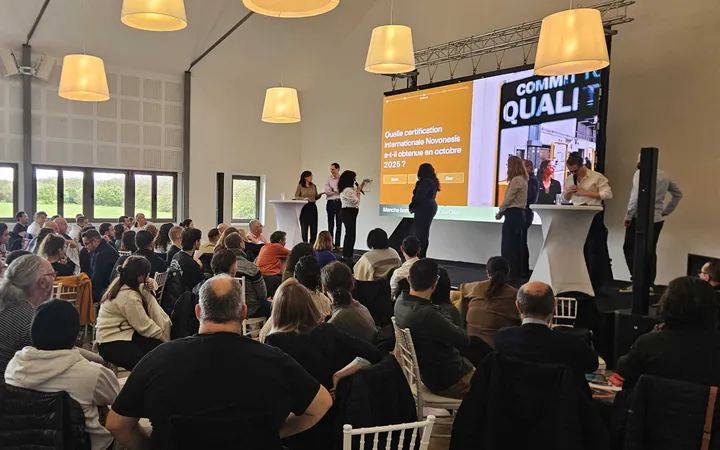 Novonesis : plénière au Domaine du Palladium, le grand écran affiche une question du quiz sur la certification obtenue en octobre 2025, des participants sont sur scène et le public est vu de dos