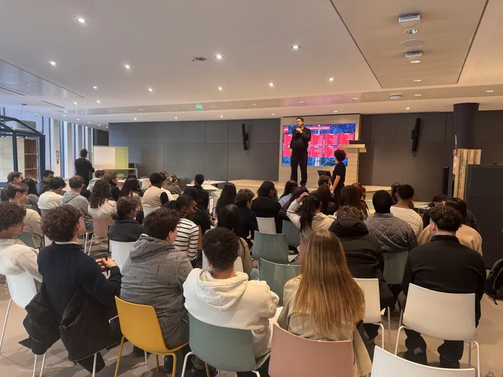 SFR 2026 : plénière de Giga City dans la cafétéria du campus, les nouveaux alternants face au grand écran et aux animateurs