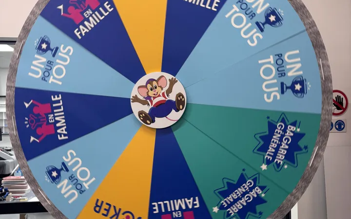 Siblu Party Game : la grande roue imprimée du jeu TV, avec ses cases Un pour tous, En famille, Bagarre générale et Joker autour de la mascotte MAX